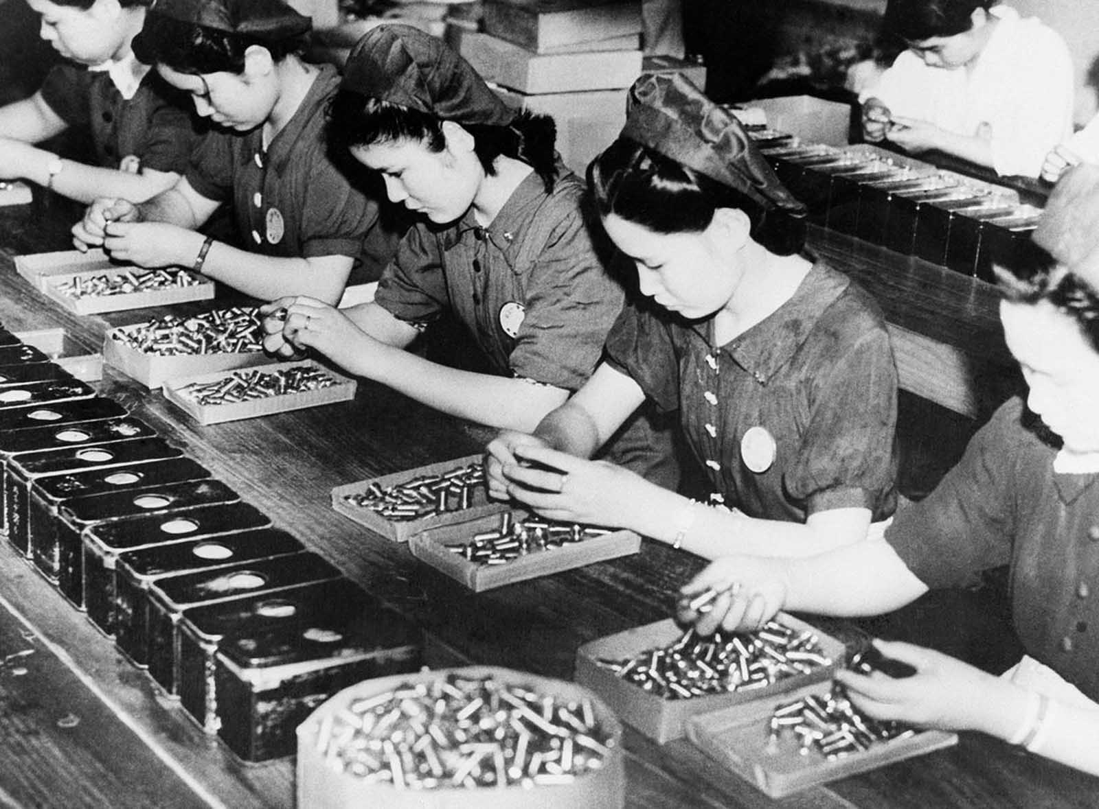 Japanese women look for possible flaws in the empty shells in a factory in Japan, on September 30, 1941.
