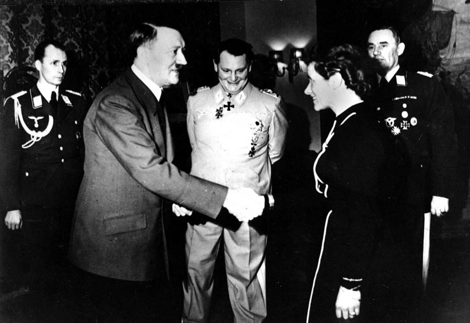 he German Aviatrix, Captain Hanna Reitsch, shakes hands with German chancellor Adolf Hitler after being awarded the Iron Cross second class at the Reich Chancellory in Berlin, Germany, in April 1941, for her service in the development of airplane armament instruments during World War II. In back, center is Reichsmarshal Hermann Goering. At the extreme right is Lt. Gen. Karl Bodenschatz of the German air ministry.