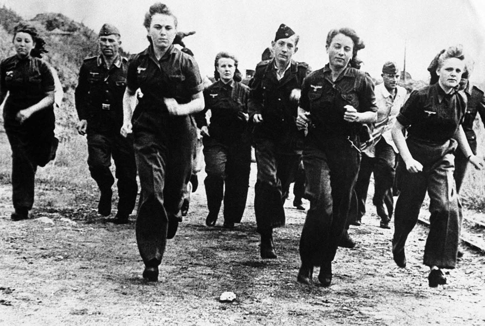 More and more girls are joining the Luftwaffe under Germany's total conscription campaign. They are replacing men transferred to the army to take up arms instead of planes against the advancing allied forces. Here, German girls are shown in training with men of the Luftwaffe, somewhere in Germany, on December 7, 1944.