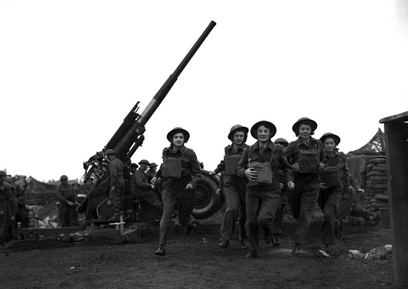 Ack-Ack Girls, members of the Auxiliary Territorial Service (ATS), run to action at an anti-aircraft gun emplacement in the London area on May 20, 1941 when the alarm is sounded.
