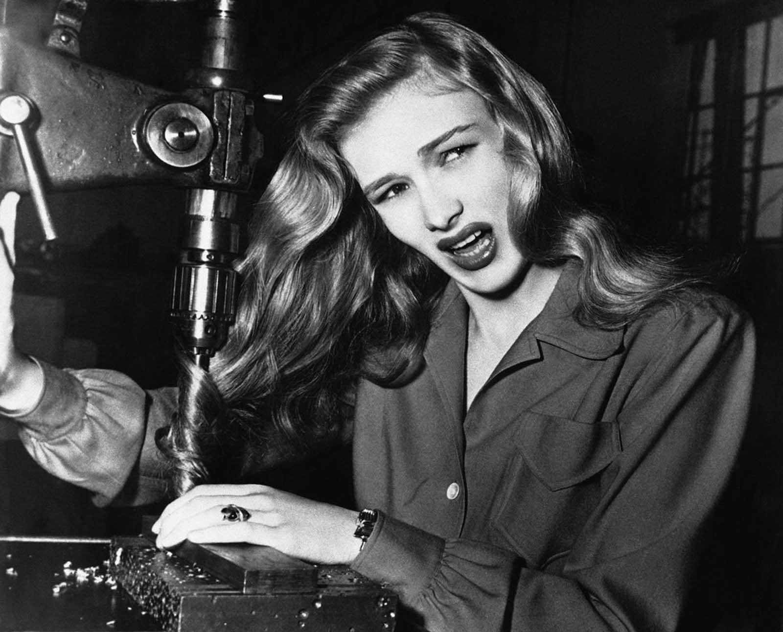 American film actress Veronica Lake, illustrates what can happen to women war workers who wear their hair long while working at their benches, in a factory somewhere in America, on November 9, 1943.