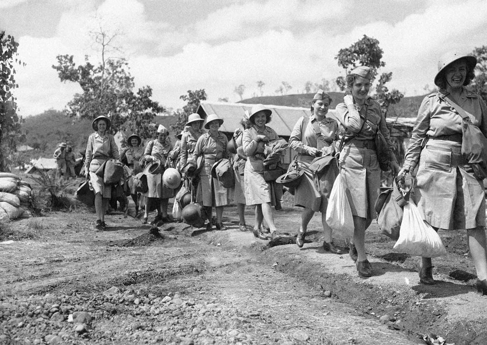 The first contingent of U.S. Army nurses to be sent to an Allied advanced base in New Guinea carry their equipment as they march single file to their quarter on November 12, 1942. The first four in line from right are: Edith Whittaker, Pawtucket, Rhode Island,; Ruth Baucher, Wooster, O.; Helen Lawson, Athens, Tennessee,; and Juanita Hamilton, of Hendersonville, North Carolina.