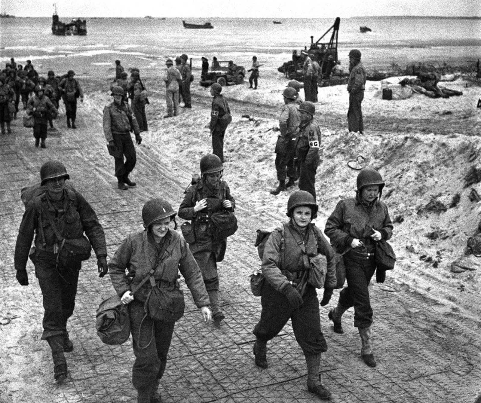U.S. nurses walk along a beach in Normandy, France on July 4, 1944, after they had waded through the surf from their landing craft. They are on their way to field hospitals to care for the wounded allied soldiers.