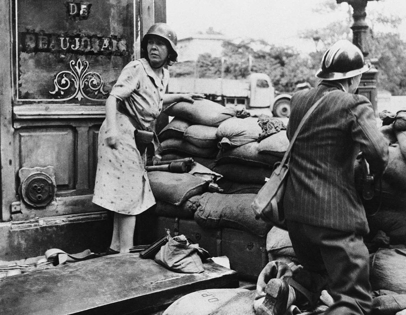 A French man and woman fight with captured German weapons as both civilians and members of the French Forces of the Interior took the fight to the Germans, in Paris in August of 1944, prior to the surrender of German forces and the Liberation of Paris on August 25.