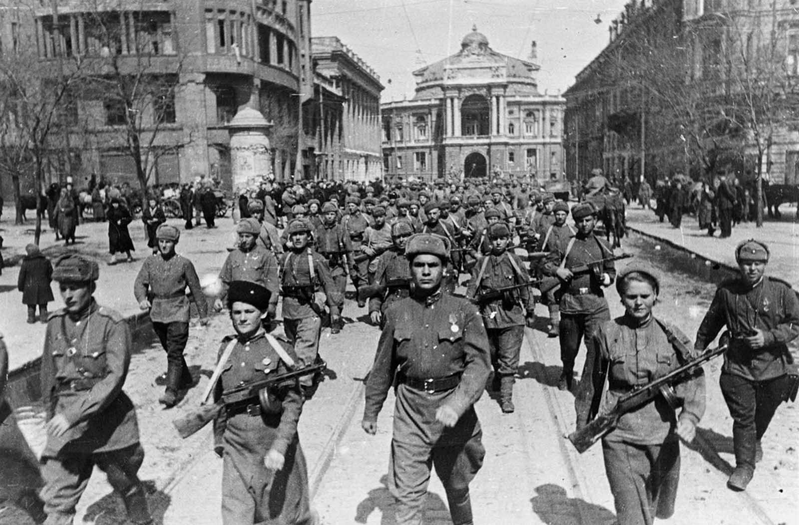 62nd Stalingrad Army on the streets of Odessa (The 8th Guard of the Army of General Chuikov on the streets of Odessa) in April of 1944. A large group of Soviet soldiers, including two women in front, march down a street.