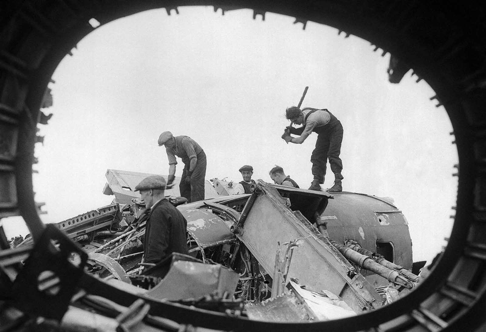British workers in a salvage yard break up the remains of wrecked German raiders which were shot down over England, on August 26, 1940.