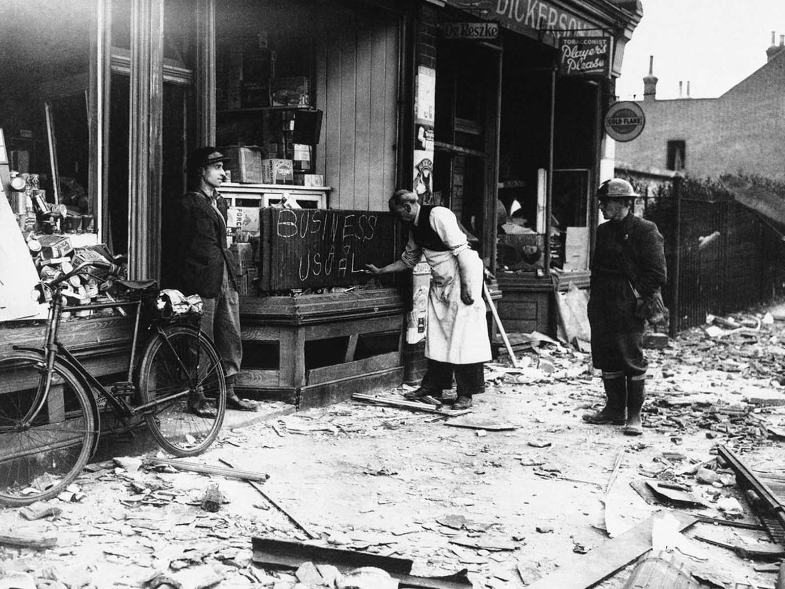 Undaunted by a night of German air raids in which his store front was blasted, a shopkeeper opens up the morning after for