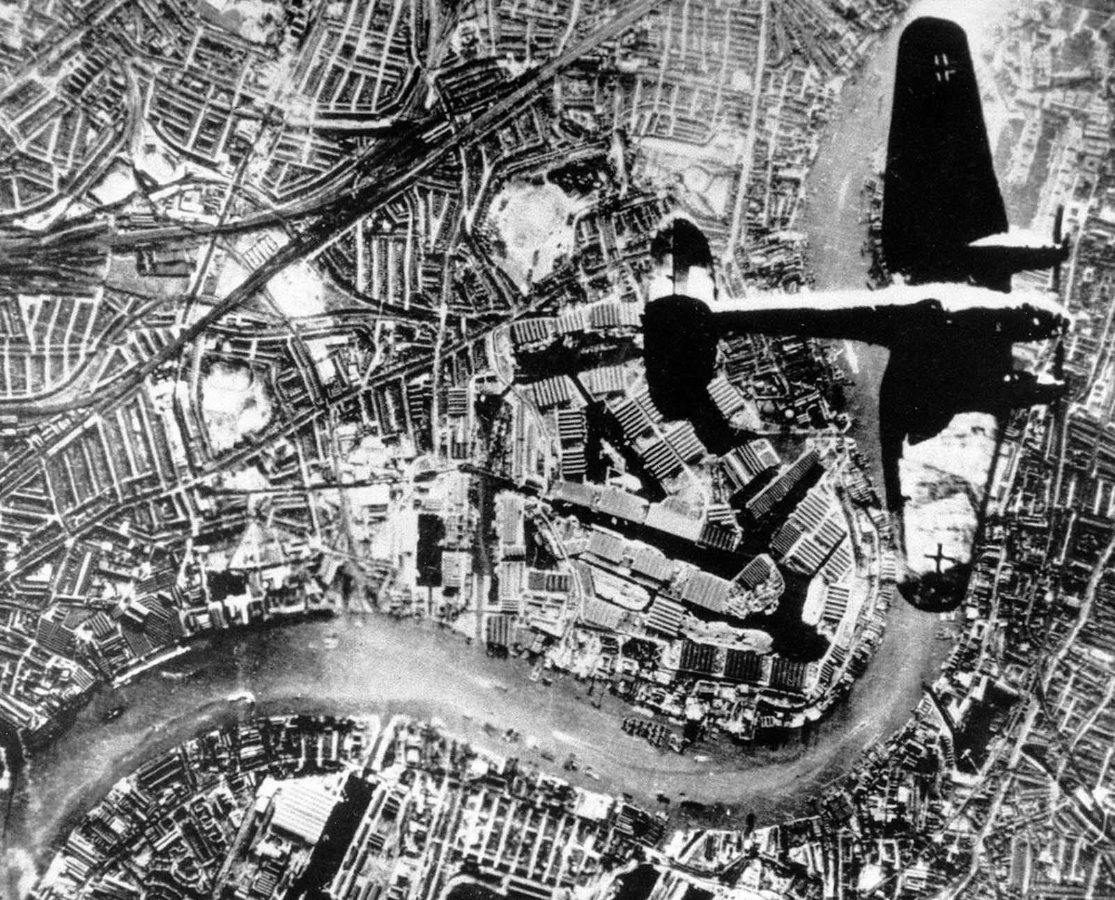 A Nazi Heinkel He 111 bomber flies over London in the autumn of 1940. The Thames River runs through the image.