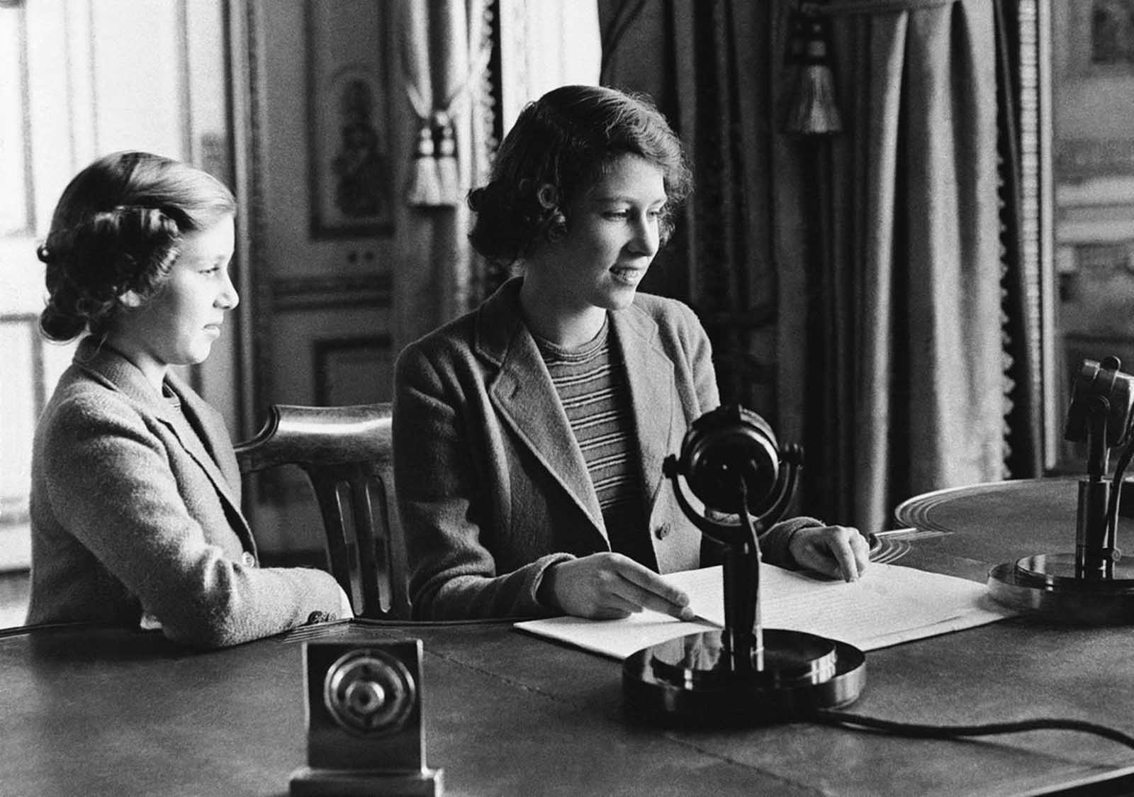 Princess Elizabeth of England (center), 14-year-old heiress apparent to the British throne, makes her broadcast debut, delivering a three-minute speech to British girls and boys evacuated overseas, on October 22, 1940, in London, England. She is joined in bidding good-night to her listeners by her sister, Princess Margaret Rose.