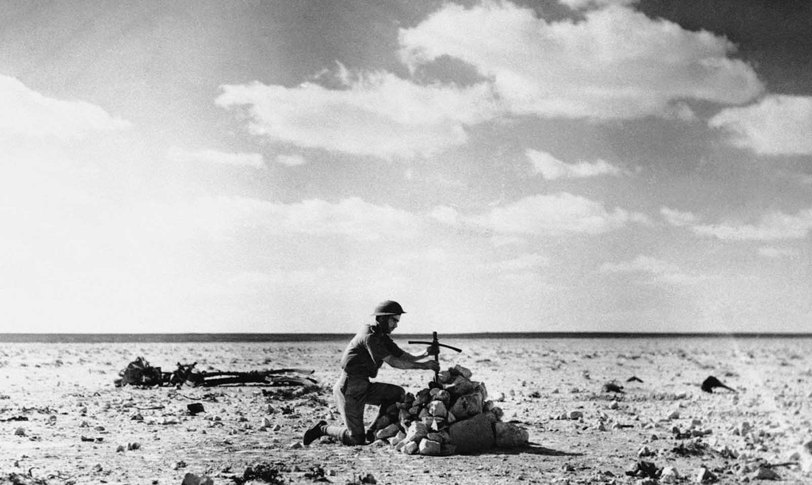 An RAF Airman places a cross, made from the wreckage of an Aircraft, over a grave on December 27, 1940, containing the bodies of five Italian Airmen shot down in the Desert Battle at Mersa Matruh on October 31, 1940.