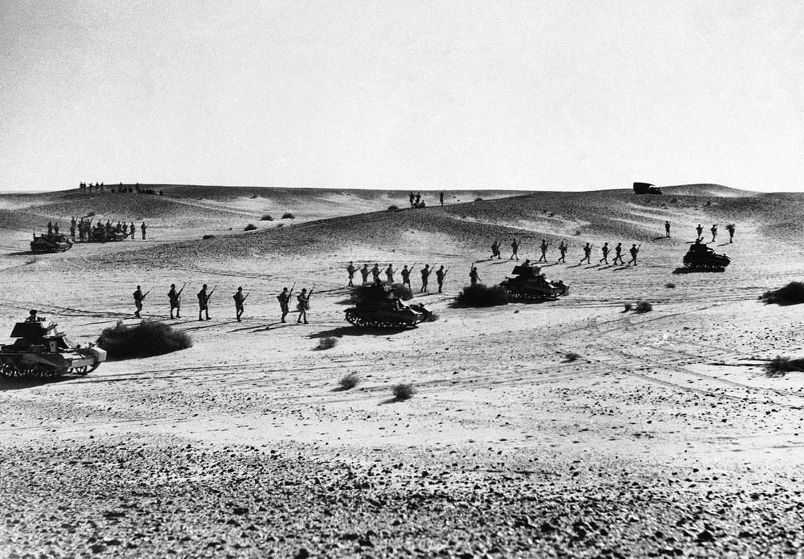 Australian troops string out behind tanks in a practice advance over North African sands, on January 3, 1941. The supporting infantry is spread out thinly as a precaution against air raids.