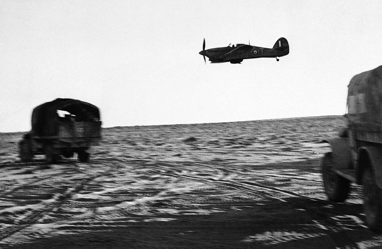 A low-flying Royal Air Force plane escorts rolling trucks of a New Zealand unit on the move in Egypt on August 3, 1942.