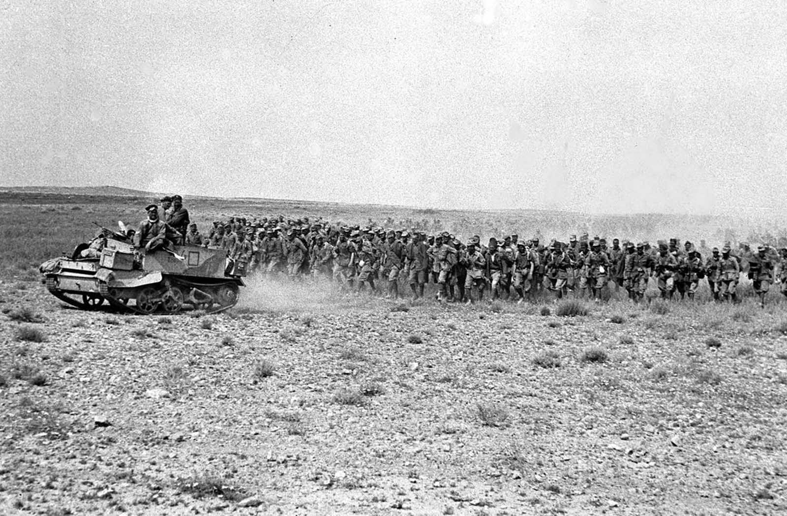 Two thousand Italian prisoners march back through Eighth Army lines, led by a Bren gun carrier, in the Tunisian desert, in March 1943. The prisoners were taken outside El-Hamma after their German counterparts pulled out of the town.