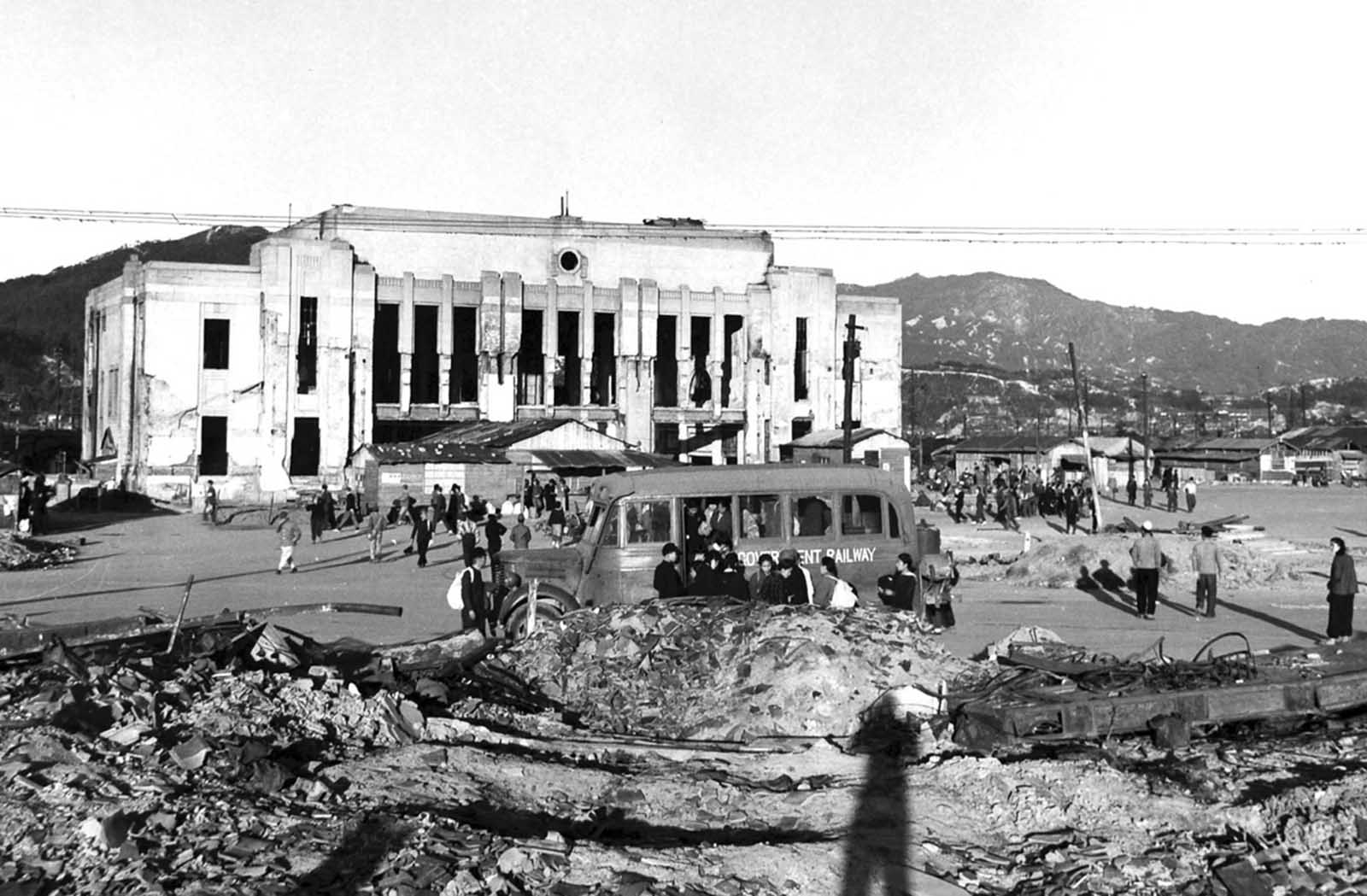 Civilians gather in front of the ruined Hiroshima Station, months after the bombing.