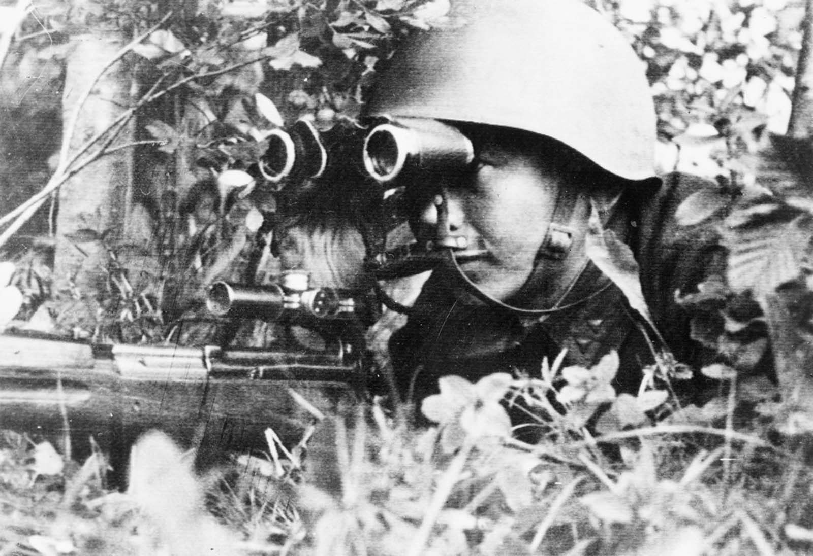 Sergeant P. Dorzhiev, a Russian sniper who killed 181 Germans on the Leningrad front, looking through binoculars, and holding a rifle, sometime in 1942.