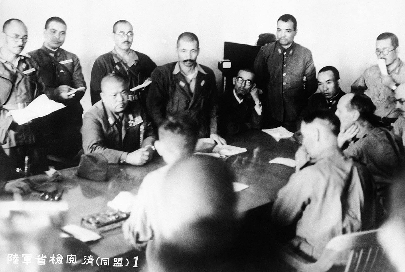 The conference at which Singapore surrendered on February 15, 1942. Man seated at left, facing camera, is identified as Lieut. Gen. Tomoyuki Yamashita, the Japanese Commander. Man in right foreground, profile to camera, is identified as Lieut. Gen. A. E. Percival, British commander.