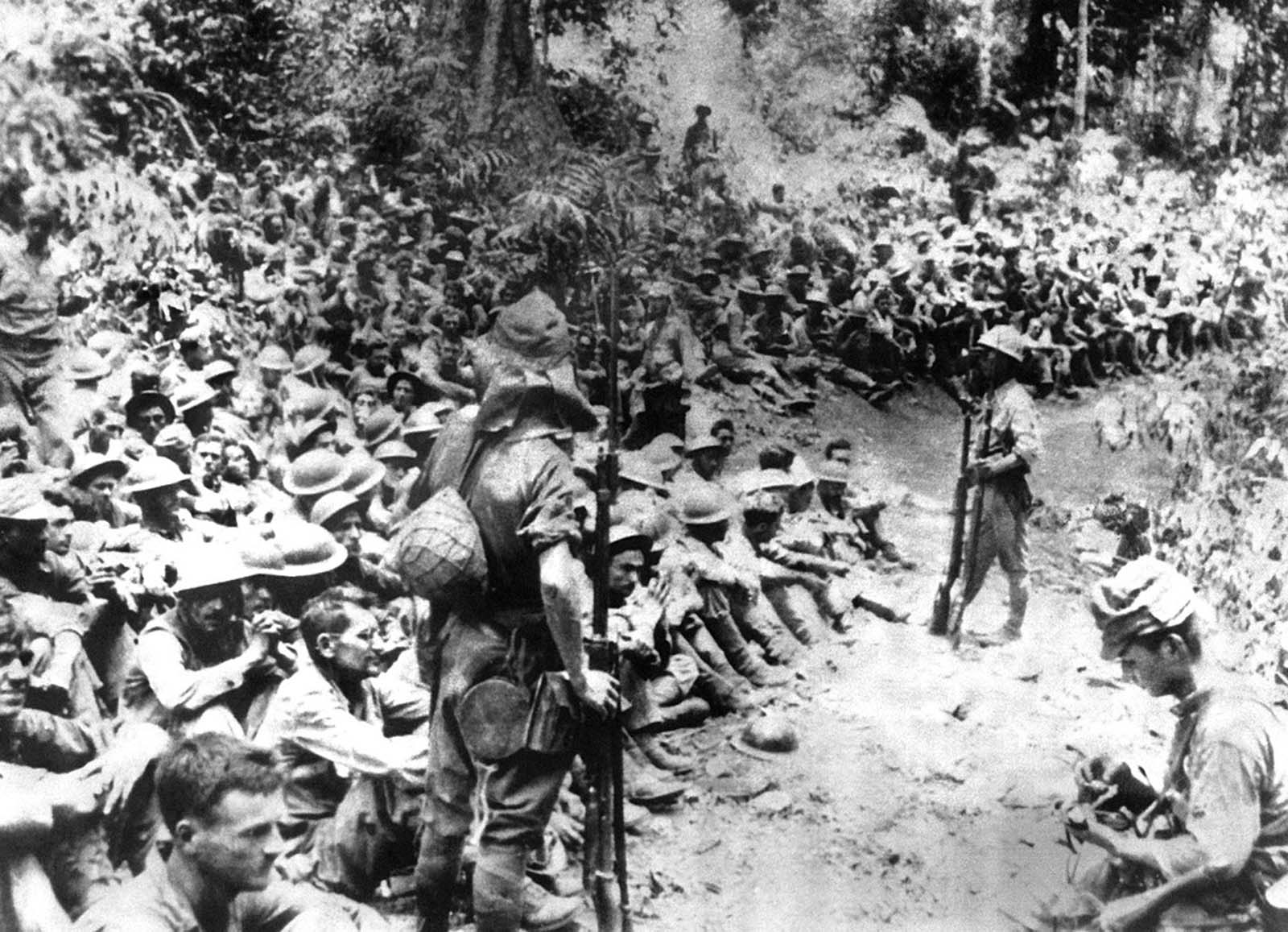 Japanese soldiers stand guard over American war prisoners just before the start of the