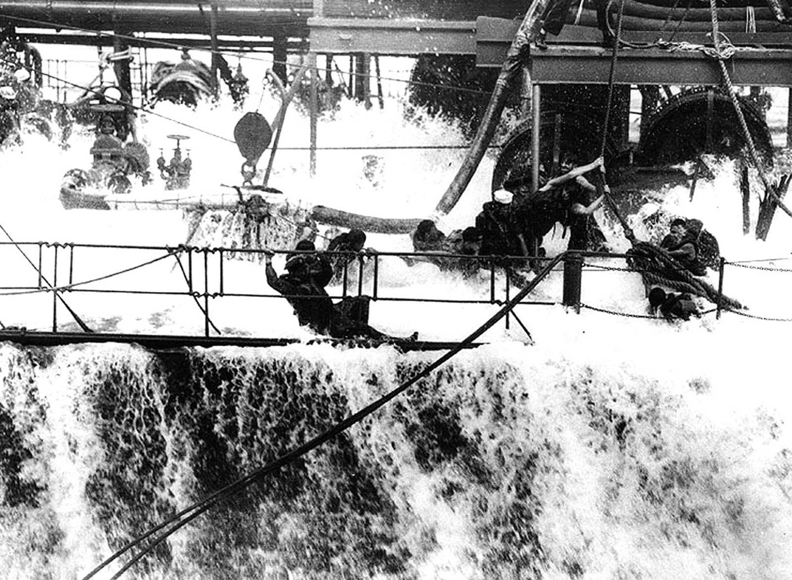 A wave breaks over the main deck of the fleet oiler USS Neosho, engulfing the hose crew, as she refuels USS Yorktown in early May 1942, shortly before the Battle of Coral Sea in the South Pacific. The Neosho was lost in that battle.