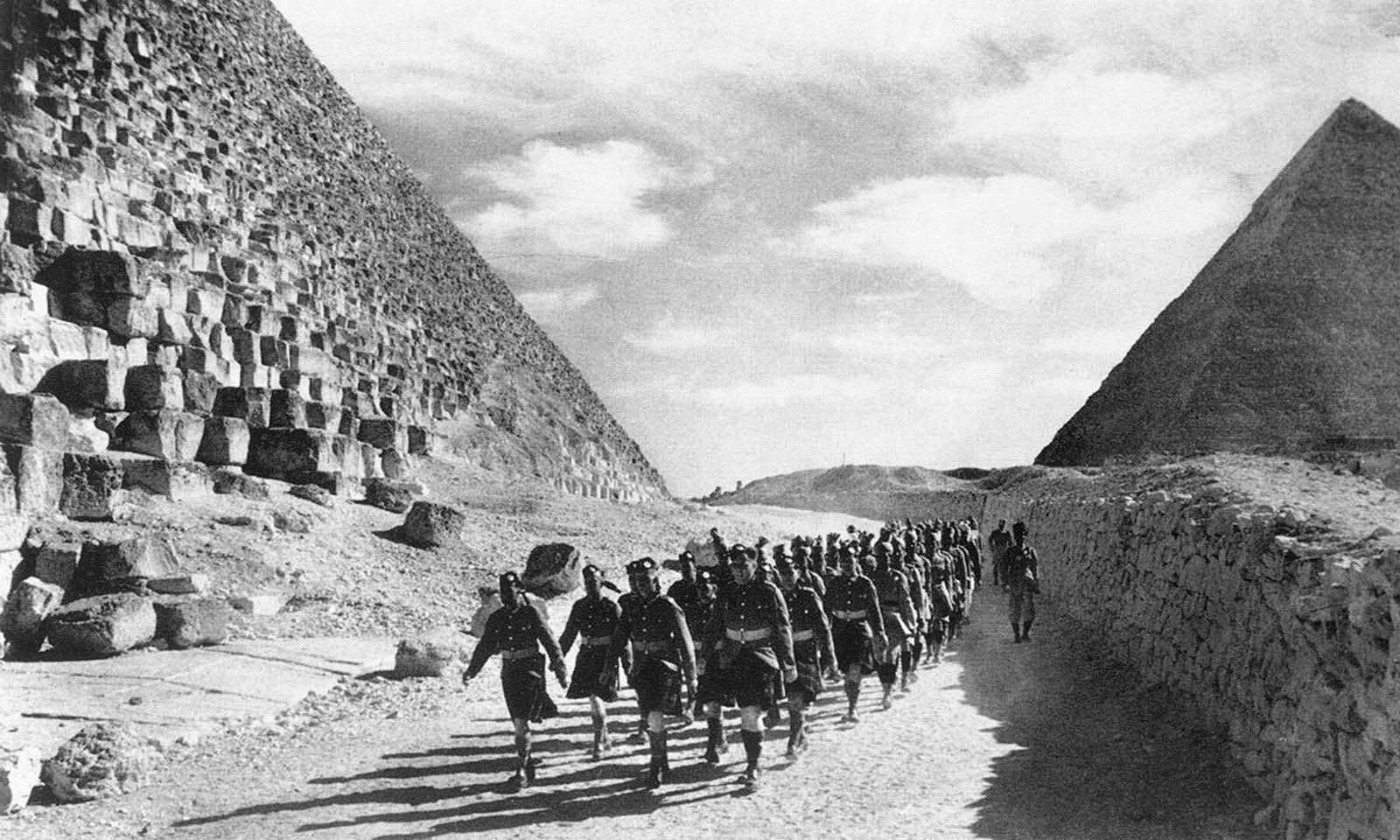 Cameron Highlanders, a Scottish infantry regiment of the British Army, and Indian troops march past the Great Pyramid in the North African Desert, on December 9, 1940.