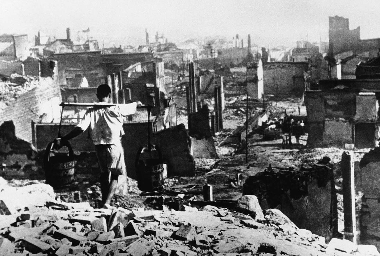 With nothing but devastation confronting him, this Chinese waterboy still carried on after four days and nights of aerial bombardment at the hands of Japanese warplanes, in Chongqing, China, on August 10, 1940.