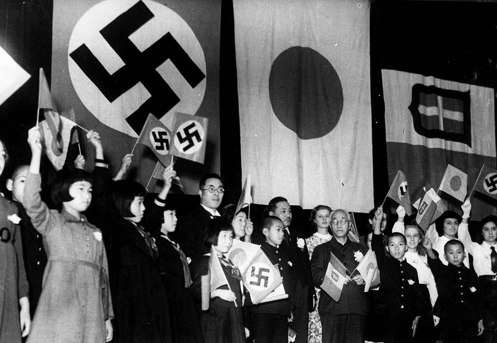 Children of Japan, Germany, and Italy meet in Tokyo to celebrate the signing of the Tripartite Alliance between the three nations, on December 17, 1940. Japanese education minister Kunihiko Hashida, center, holding crossed flags, and Mayor Tomejiro Okubo of Tokyo were among the sponsors.
