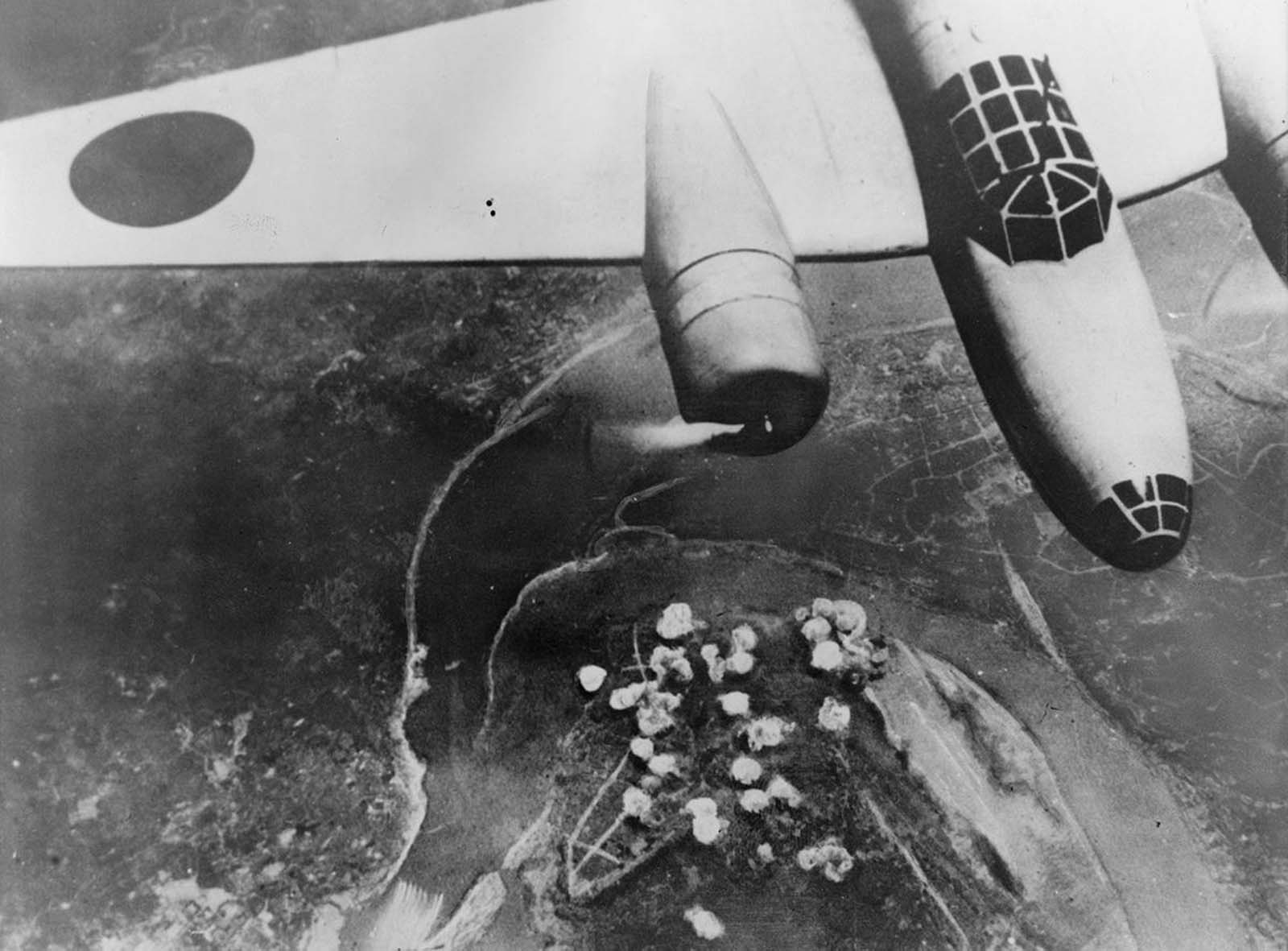 A Japanese bomber in flight on September 14, 1940. Below, smoke rises from a cluster of bombs dropped on Chongqing, China, near a bend of the Yangtze River.