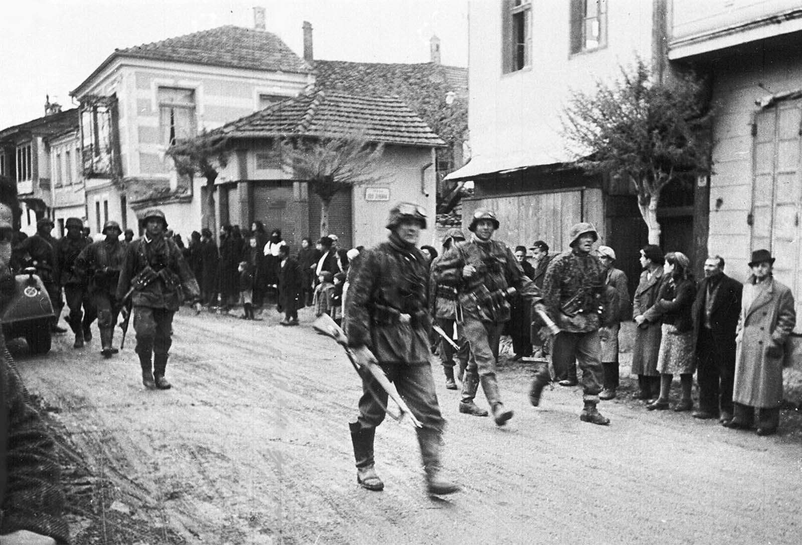 A squad of German soldiers pass through a Greek village, during the occupation of Greece, in May 1941.
