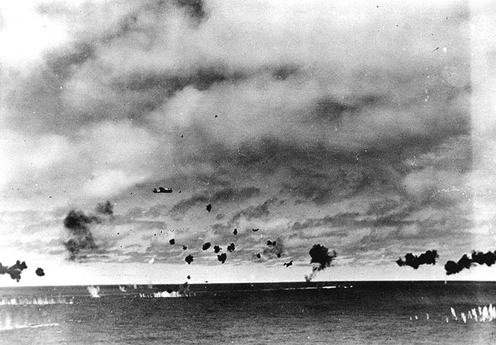 Japanese Type 97 shipboard attack aircraft from the carrier Hiryu amid heavy anti-aircraft fire, during the torpedo attack on USS Yorktown in the mid-afternoon of June 4, 1942. At least three planes are visible, the nearest having already dropped its torpedo. The other two are lower and closer to the center, apparently withdrawing. Smoke on the horizon in right center is from a crashed plane.