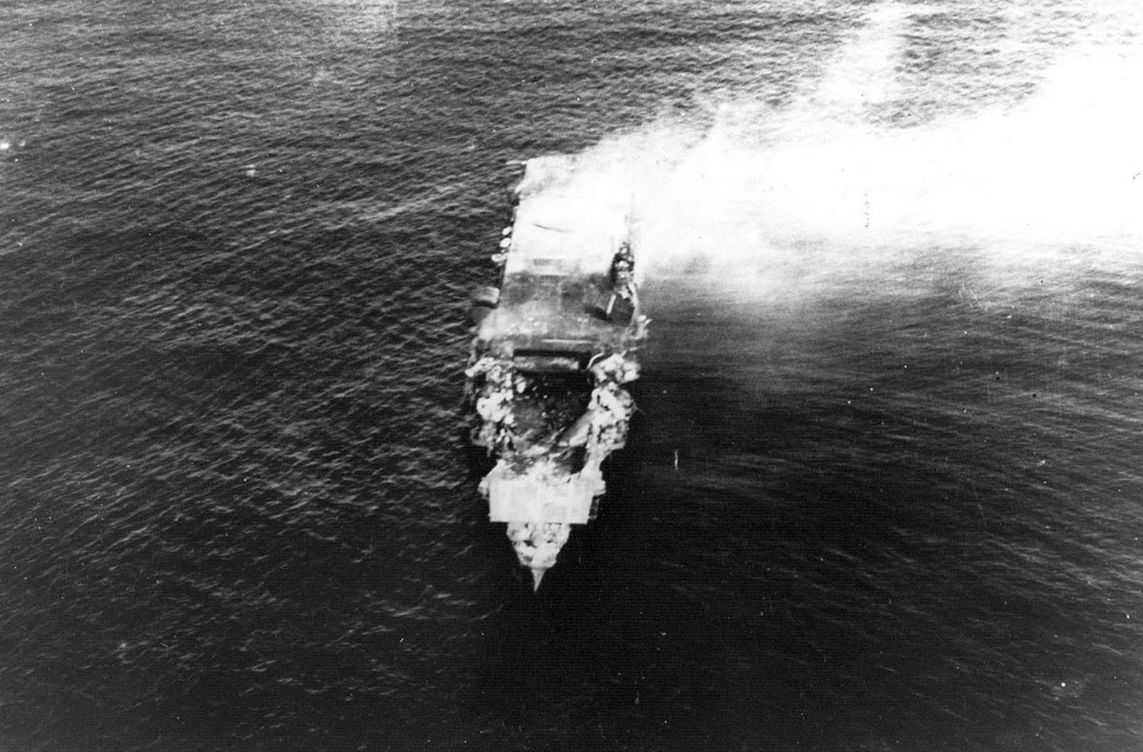The heavily damaged, burning Japanese aircraft carrier Hiryu, photographed by a plane from the carrier Hosho shortly after sunrise on June 5, 1942. Hiryu sank a few hours later. Note collapsed flight deck over the forward hangar.