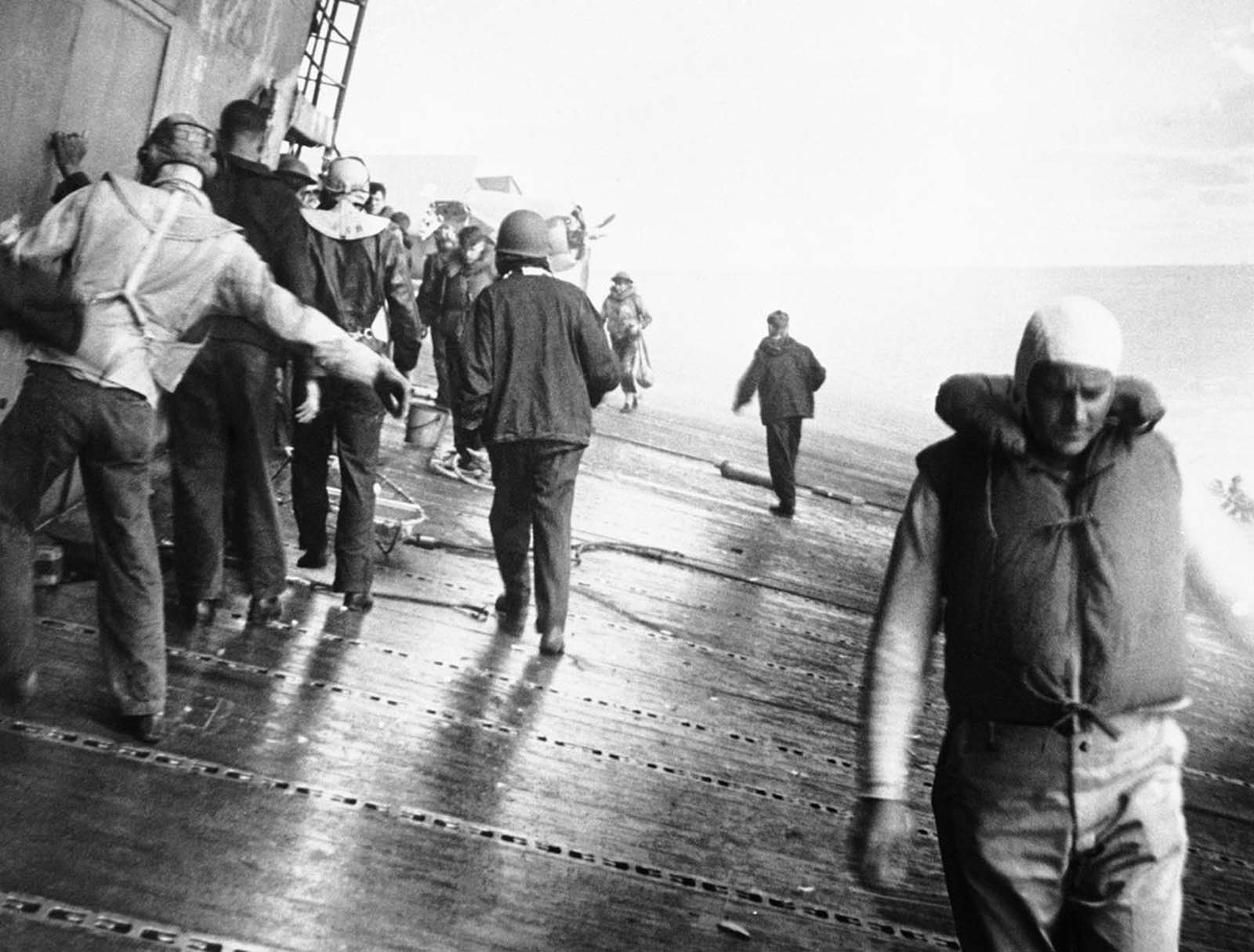 Crewmen of the USS Yorktown pick their way along the sloping flight deck of the aircraft carrier as the ship listed heavily, heading for damaged sections to see if they can patch up the crippled ship, in June of 1942.
