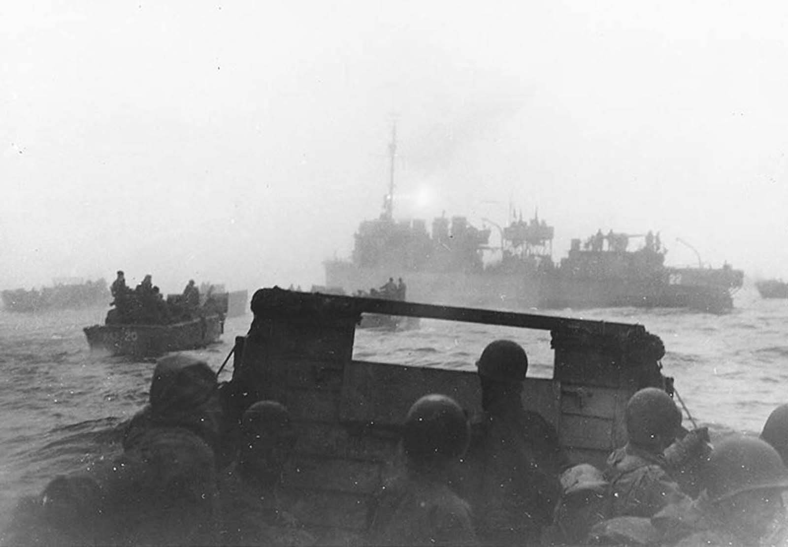 USS Pruitt leads landing craft from USS Heywood toward their landing beaches in Massacre Bay, Attu, on the first day of the May 11, 1943 invasion of Attu. Pruitt used her radar and searchlight to guide the boats nine miles through the fog. The searchlight beam is faintly visible pointing aft from atop her pilothouse. Some 15,000 American and Canadian troops successfully landed on the island.