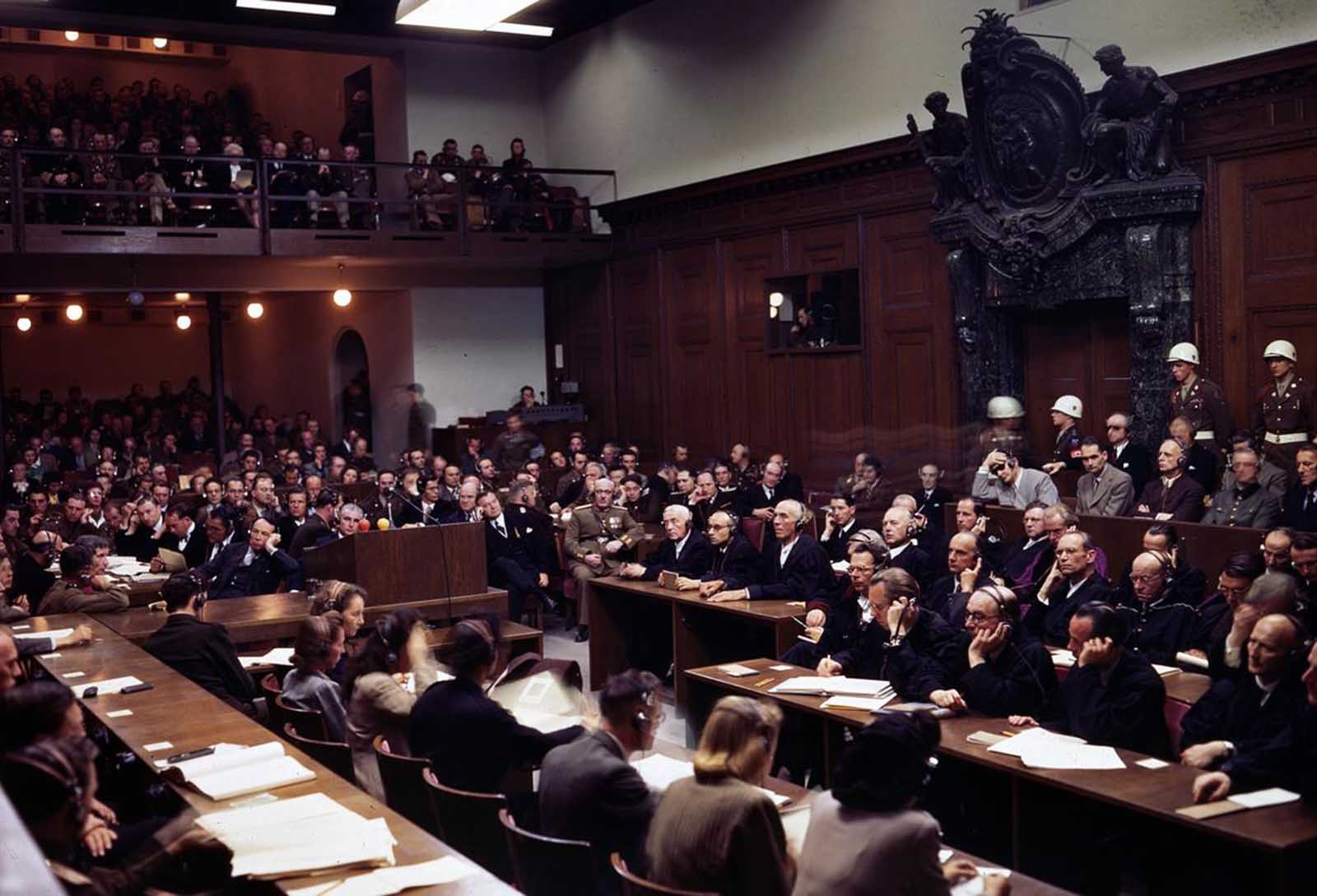 The interior of the courtroom of the Nuremberg War Crimes Trials in 1946 during the Trial of the Major War Criminals, prosecuting 24 government and civilian leaders of Nazi Germany. Visible here is Hermann Goering, former leader of the Luftwaffe, seated in the box at center right, wearing a gray jacket, headphones, and dark glasses. Next to him sits Rudolf Hess, former Deputy Fuhrer of Germany, then Joachim von Ribbentrop, former Nazi Minister of Foreign Affairs, Wilhelm Keitel, former leader of Germany's Supreme Command (blurry face), and Ernst Kaltenbrunner, the highest ranking surviving SS-leader. Goering, von Ribbentrop, Keitel, and Kaltenbrunner were sentenced to death by hanging along with 8 others -- Goering committed suicide the night before the execution. Hess was sentenced to life imprisonment, which he served at Spandau Prison, Berlin, where he died in 1987.