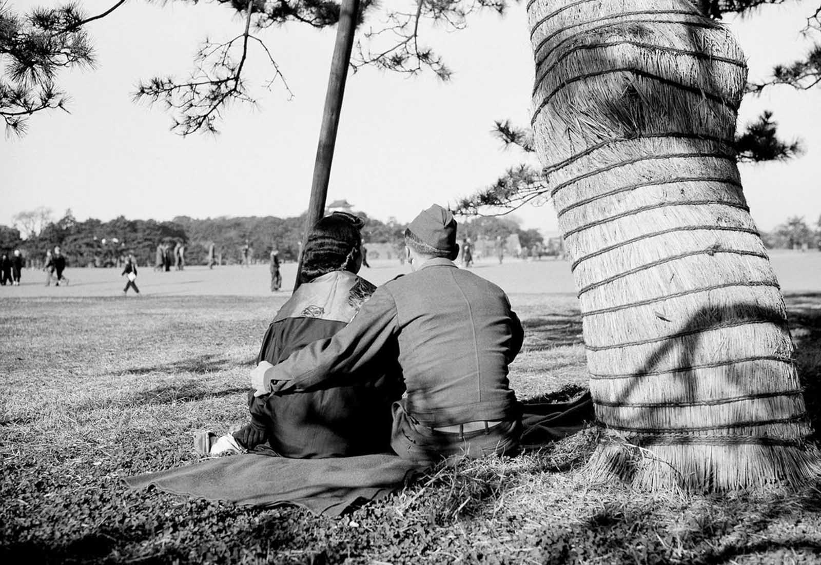 An American G.I. places his arm around a Japanese girl as they view the surroundings of Hibiya Park, near the Tokyo palace of the emperor, on January 21, 1946.