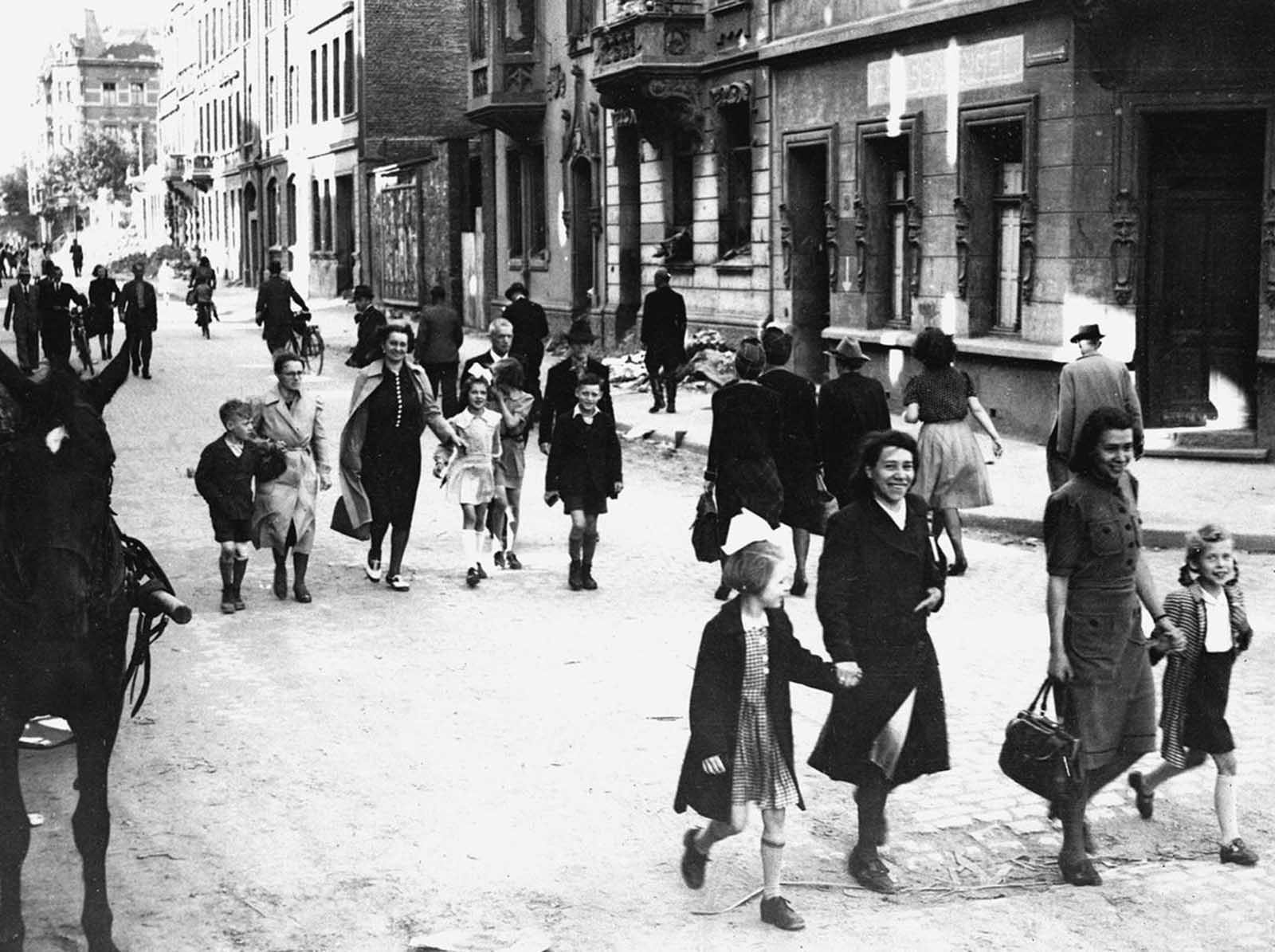 German mothers walk their children to school through the streets of Aachen, Germany, on June 6, 1945, for registration at the first public school to be opened by the U.S. military government after the war.
