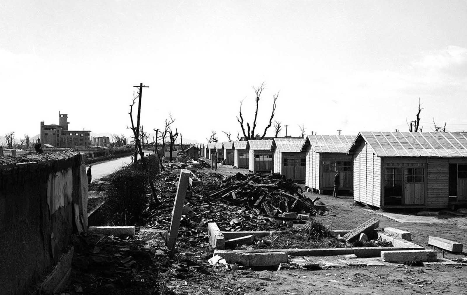 New buildings (right) rise out of the ruins of Hiroshima, Japan, on March 11, 1946. These single story homes built along a hard-surfaced highway are part of the program by the Japanese government to rebuild devastated sections of the country. At left background are damaged buildings whose masonry withstood the effects of the first atomic bomb ever detonated as a weapon.