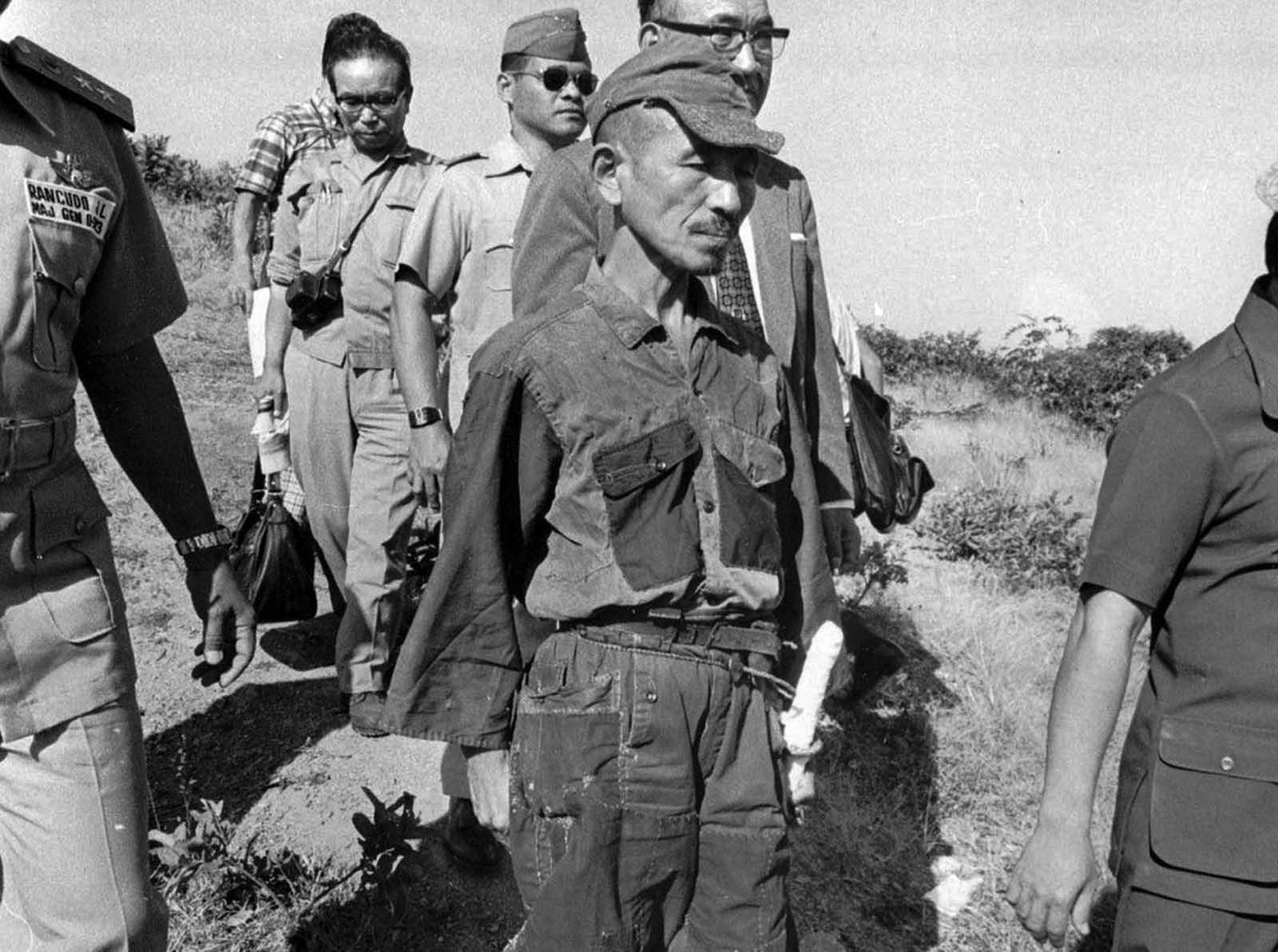 In March of 1974, some 29 years after the official end of World War II, Hiroo Onoda, a former Japanese Army intelligence officer, walks out of the jungle of Lubang Island in the Philippines, where he was finally relieved of duty. He handed over his sword (hanging from his hip in photo), his rifle, ammunition and several hand grenades. Onoda had been sent to Lubang Island in December of 1944 to join an existing group of soldiers and hamper any enemy attacks. Allied forces overtook the island just a few months later, capturing or killing all but Onoda and three other Japanese soldiers. The four ran into the hills and began a decades-long insurgency extending well past the end of the war. Several times they found or were handed leaflets notifying them that the war had ended, but they refused to believe it. In 1950, one of the soldiers turned himself in to Philippine authorities. By 1972, Onoda's two other compatriots were dead, killed during guerrilla activities, leaving Onoda alone. In 1974, Onoda met a Japanese college dropout, Norio Suzuki, who was traveling the world, and through their friendship, Onoda's former commanding officer was located and flew to Lubang Island to formally relieve Onoda of duty, and bring him home to Japan. Over the years, the small group had killed some 30 Filipinos in various attacks, but Onoda ended up going free, after he received a pardon from President Ferdinand Marcos.