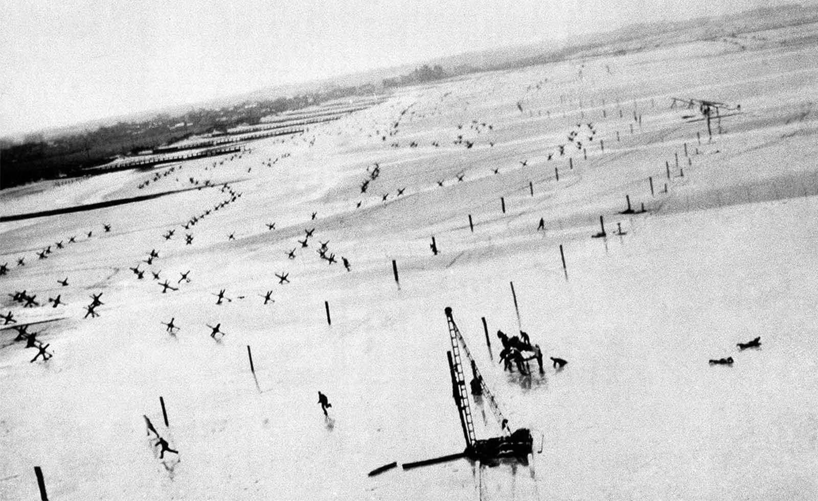 A low-flying Allied plane sends German soldiers running for shelter on a beach in France, before D-Day in 1944. The fliers were taking photos of German coastal barriers in preparation for the upcoming June 6 invasion.