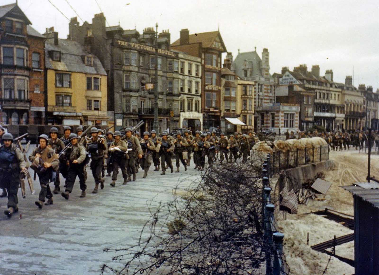 American troops march through the streets of a British port town on their way to the docks where they will be loaded into landing craft for the D-Day assault in June of 1944.