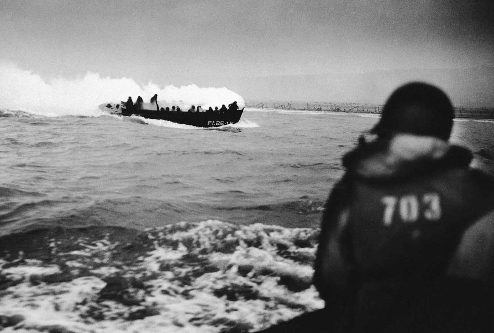 Smoke streams from a U.S. coast guard landing craft approaching the French Coast on June 6, 1944 after German machine gun fire caused an explosion by setting off an American soldier's hand grenade.