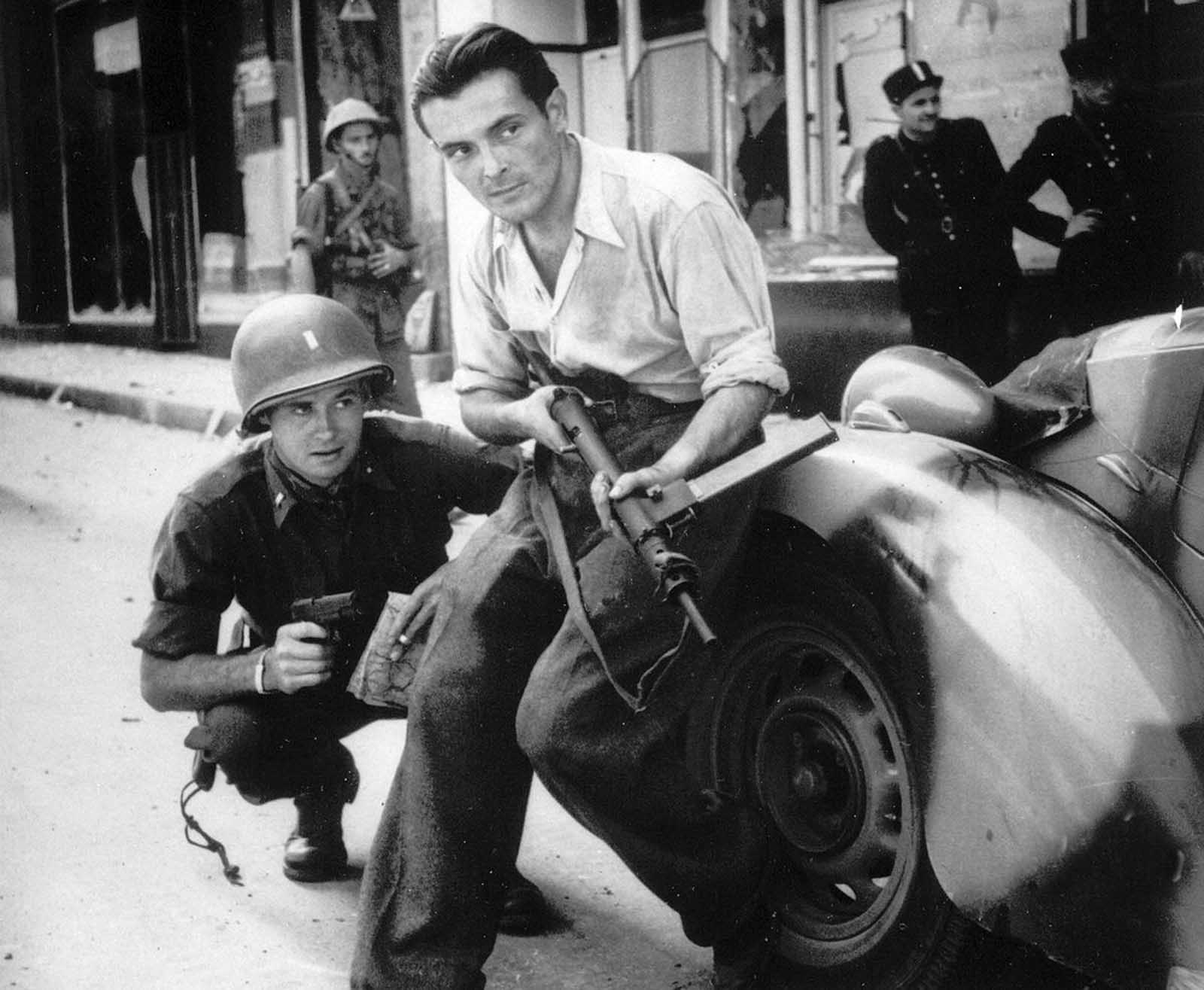 In France, an American officer and a French Resistance fighter are seen engaged in a street battle with German occupation forces during the days of liberation, August 1944, in an unknown city.