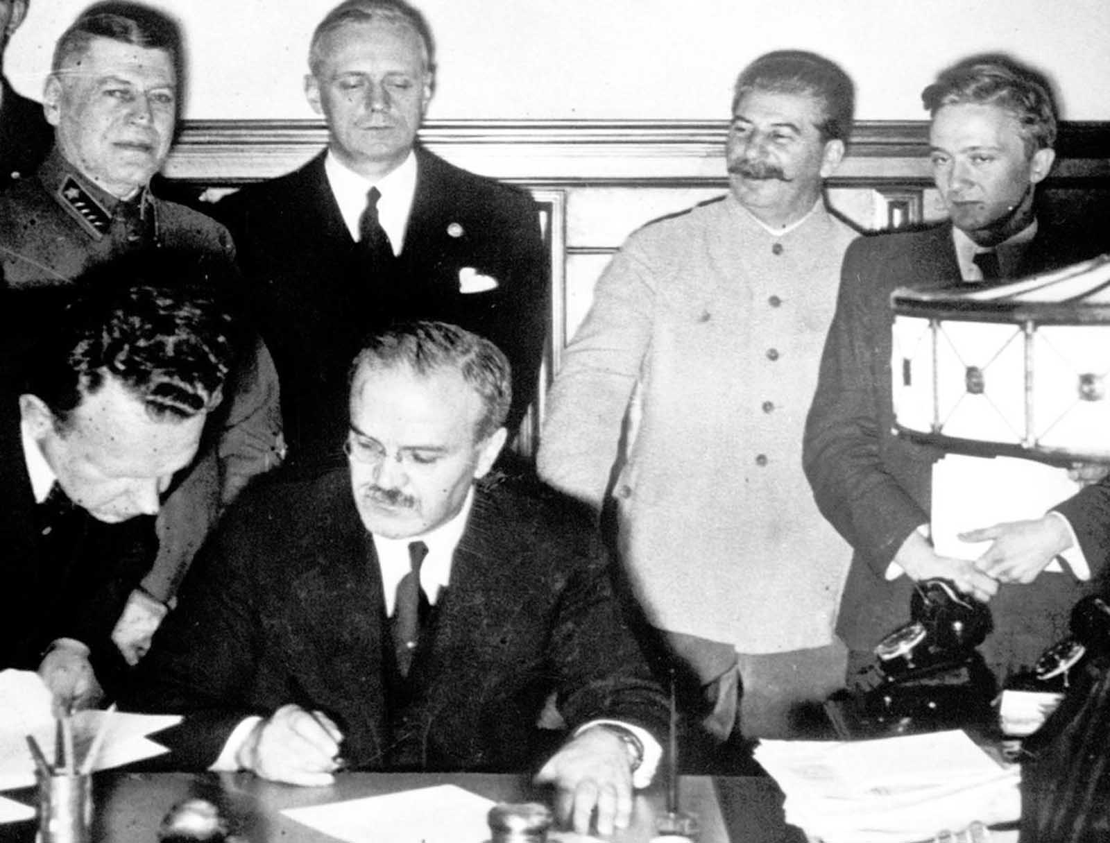 Soviet premier Josef Stalin (second from right), smiles while Soviet Foreign Minister Vyacheslav Molotov (seated), signs the non-aggression pact with German Reich Foreign Minister Joachim von Ribbentrop (third from right), in Moscow, on August 23, 1939. The man at left is Soviet Deputy Defense Minister and Chief of the General Staff, Marshal Boris Shaposhnikov. The nonaggression pact included a secret protocol dividing eastern Europe into spheres of influence in the event of a conflict. The pact now guaranteed that Hitler's troops would face no resistance from the Soviets if they invaded Poland, bringing the war one step closer to reality.