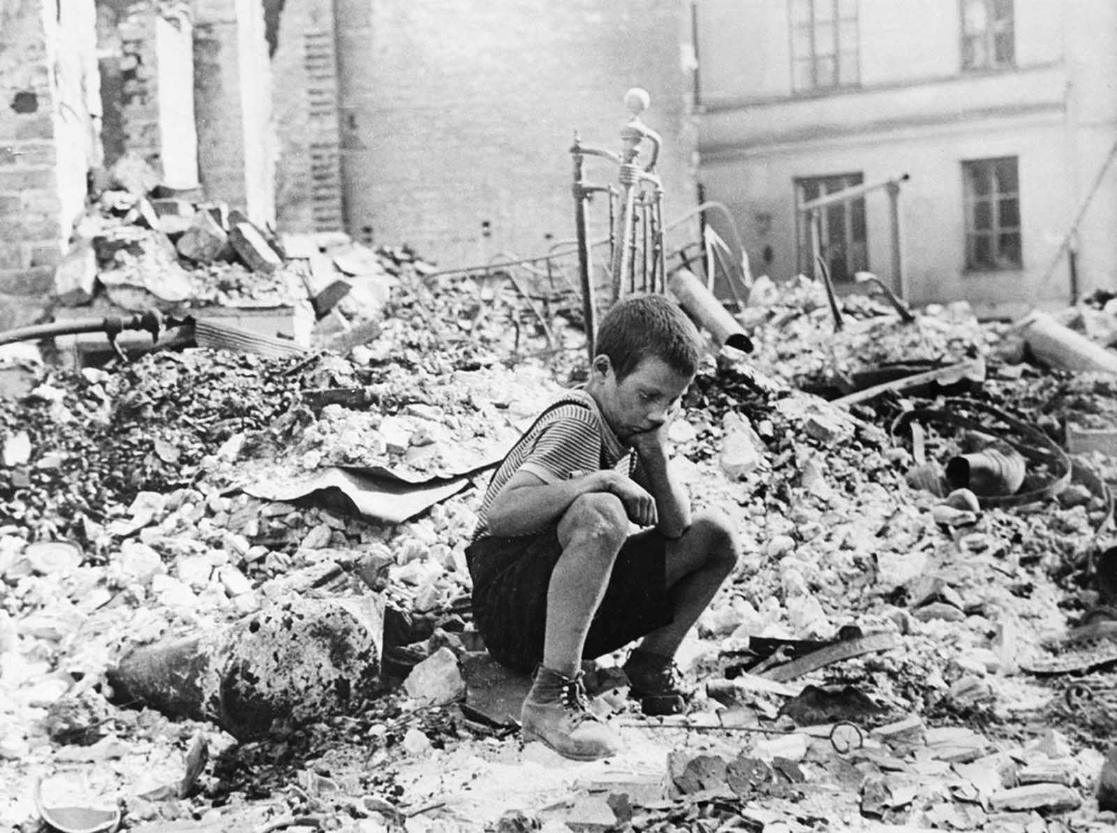 A young Polish boy returns to what was his home and squats among the ruins during a pause in the German air raids on Warsaw, Poland, in September of 1939. German attacks lasted until Warsaw surrendered on September 28. One week later, the last of the Polish forces capitulated near Lublin, giving full control of Poland to Germany and the Soviet Union.