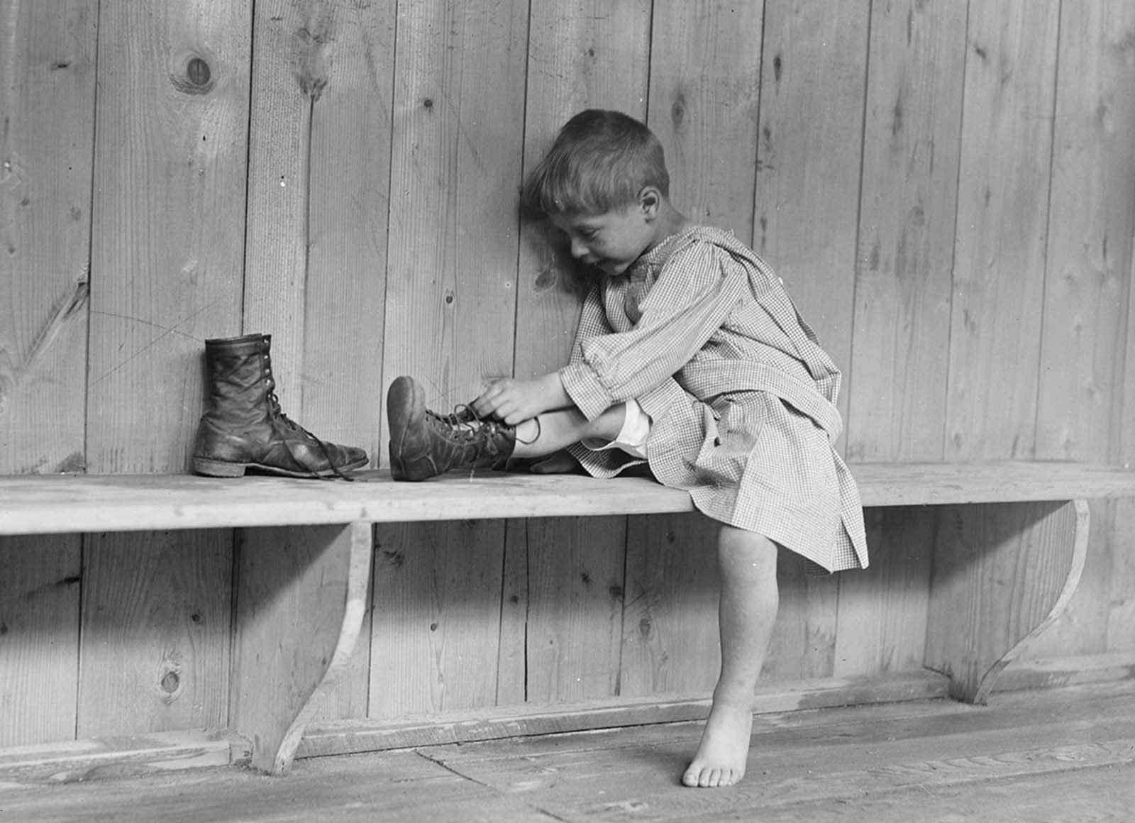 A boy puts on his new shoes at Trudeau Sanitarium, Hachette, near Paris in September of 1918.