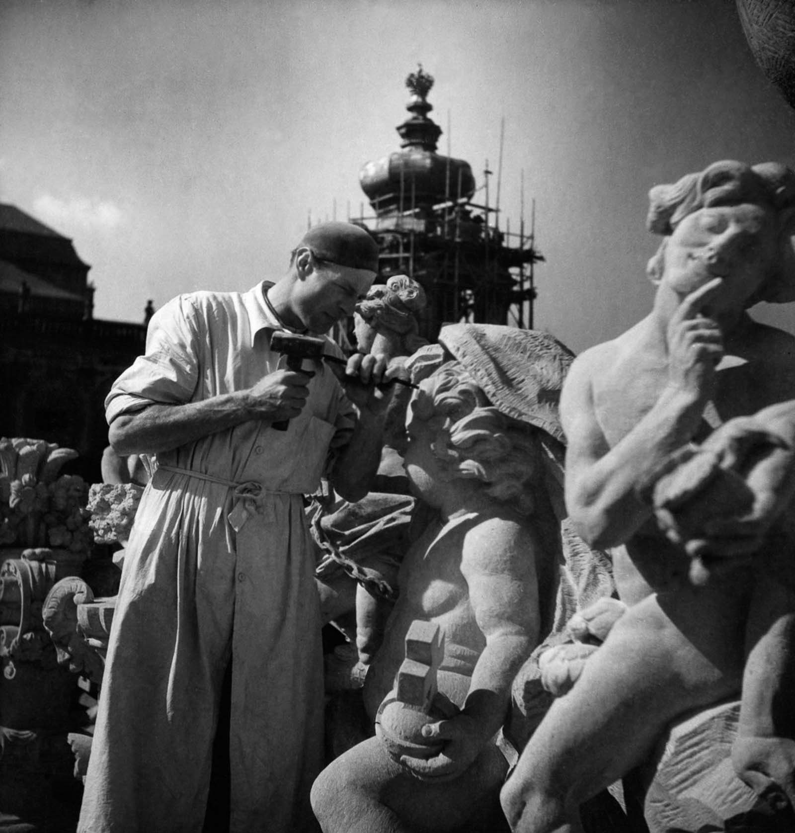 A man makes repairs to a damaged statue. 1949.