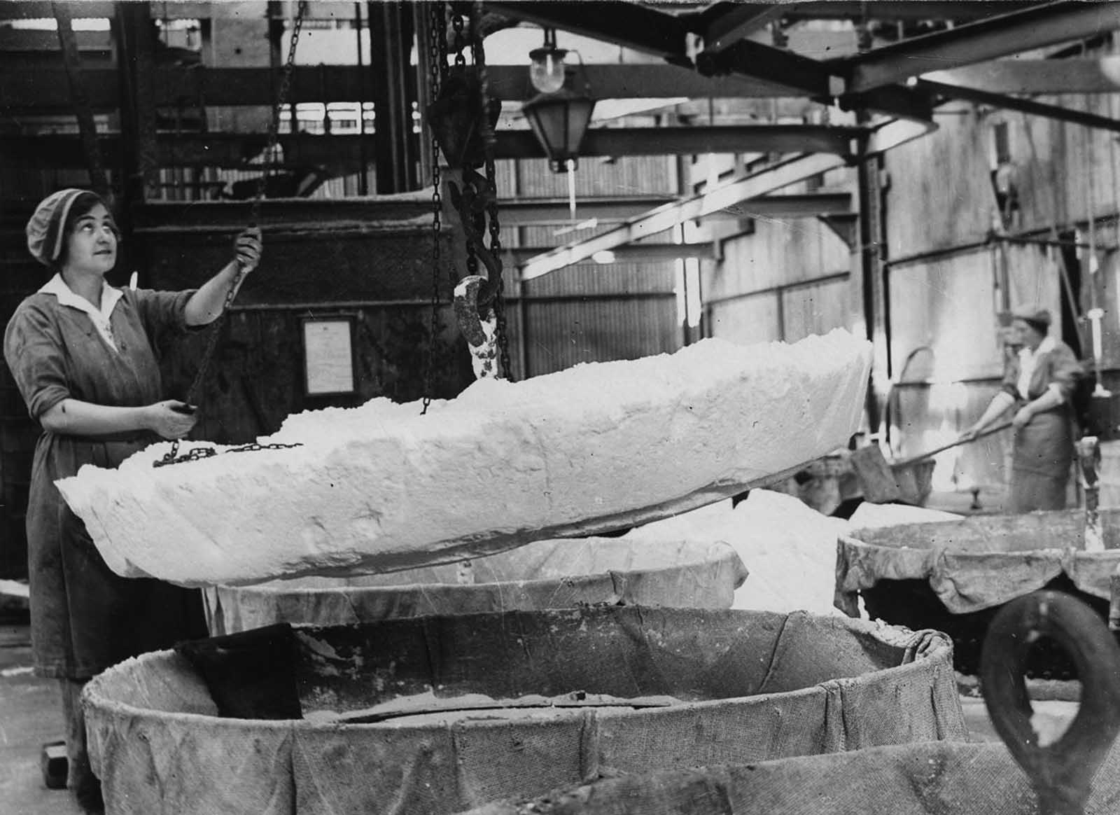 A worker hauls a cake of nitrate ammonia out of a dryer in a chemical plant.