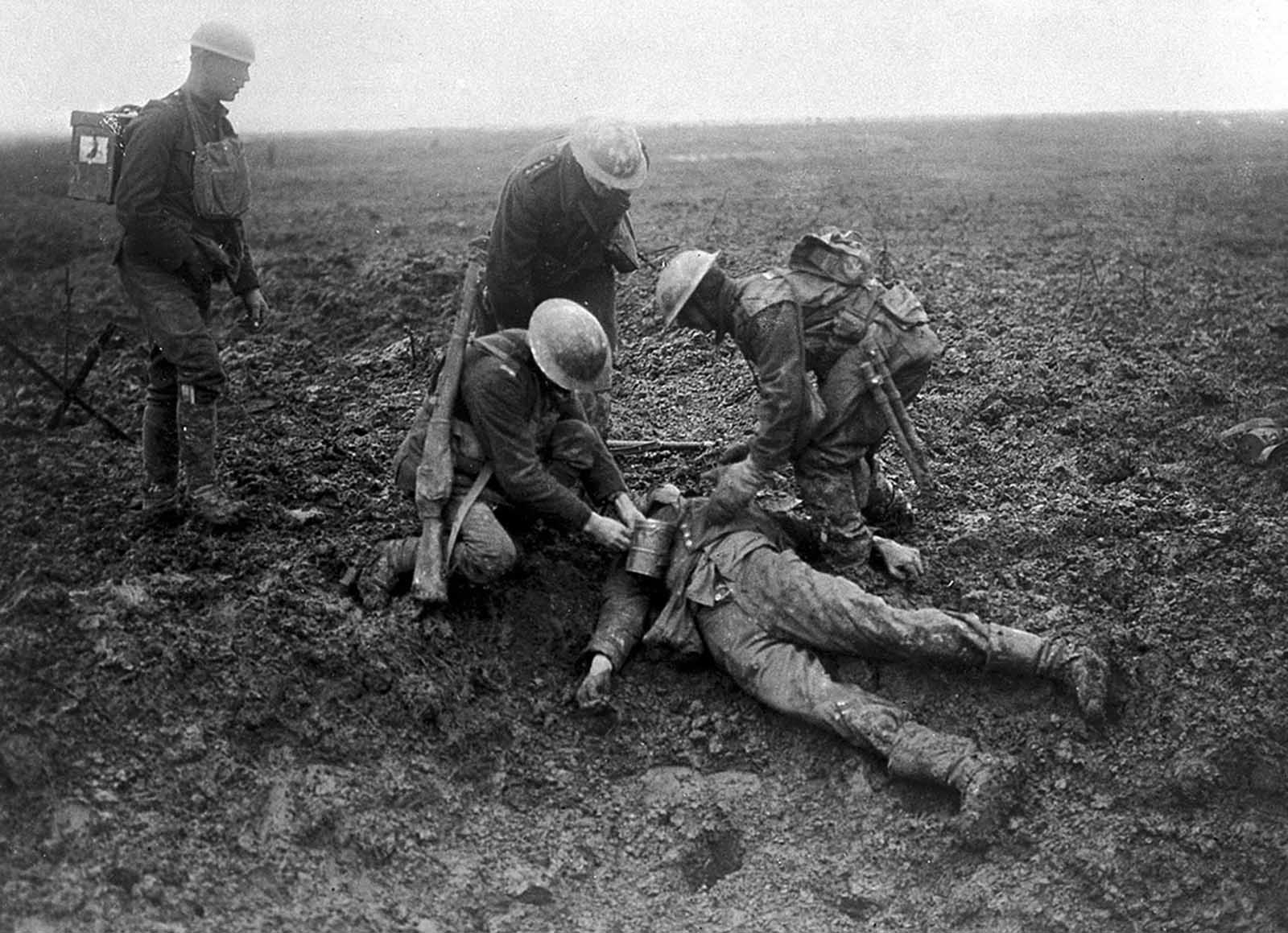 Canadian soldiers tend to a fallen German on the battlefield at the Battle of Vimy Ridge in 1917.