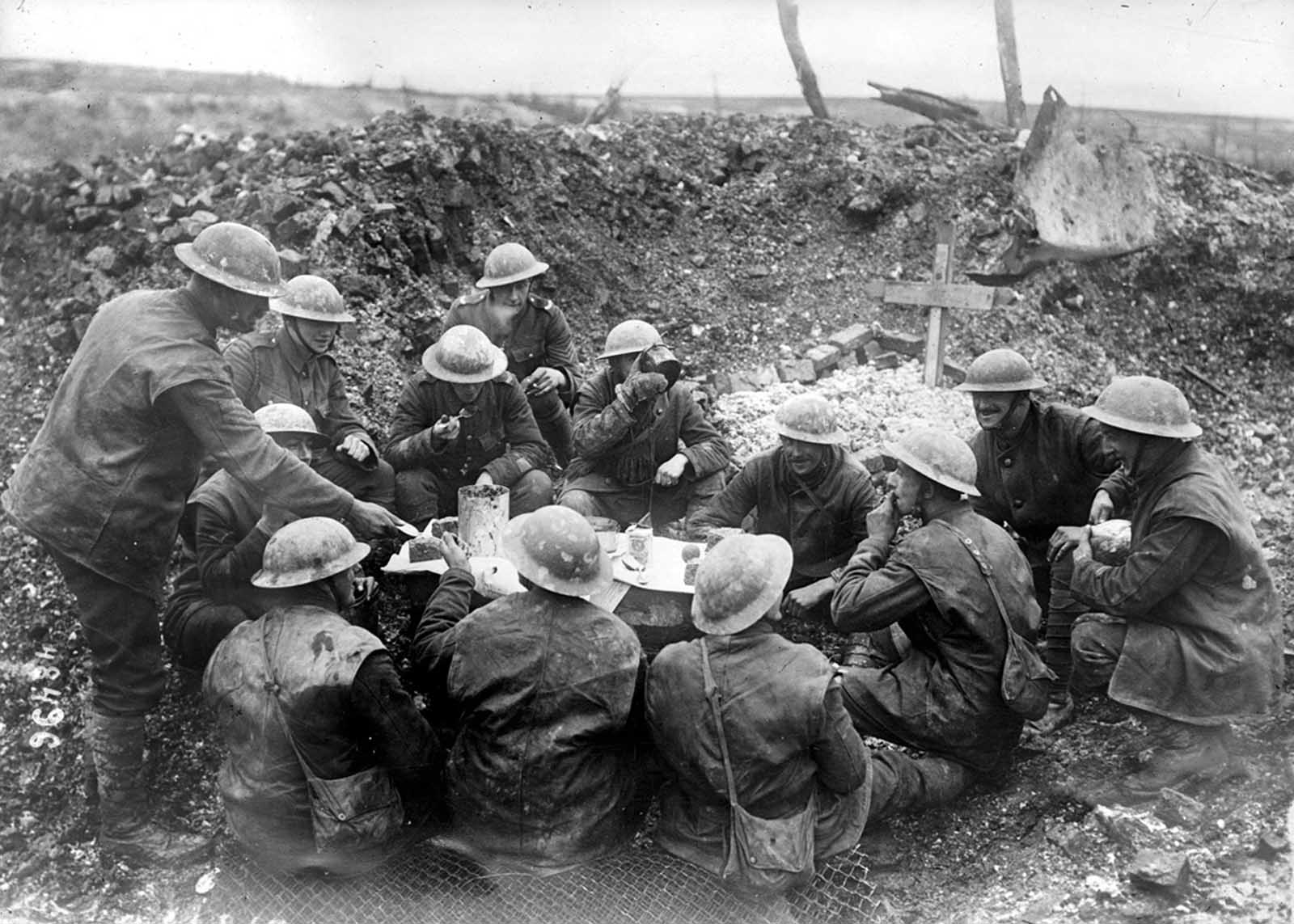 On the British front, Christmas Dinner, 1916, in a shell hole beside a grave.