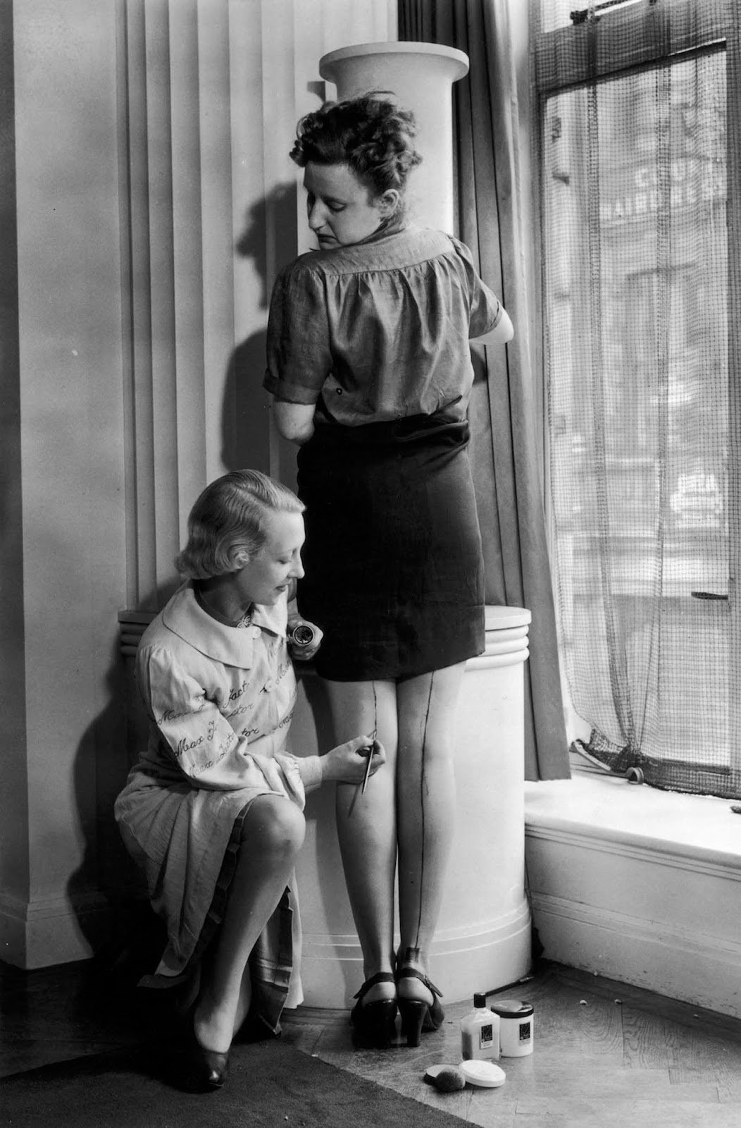 A Max Factor beautician paints a seam on a woman's leg to help create the illusion of stockings.