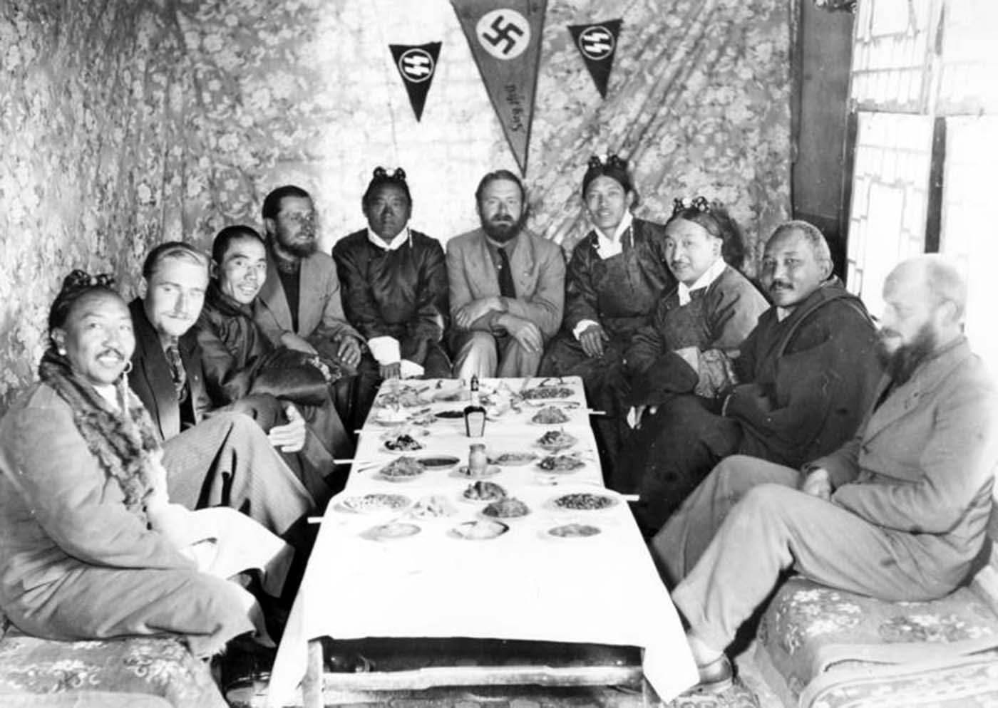 Under SS pennants and a swastika, the expedition members are entertaining some Tibetan dignitaries and the Chinese representative in Lhasa.