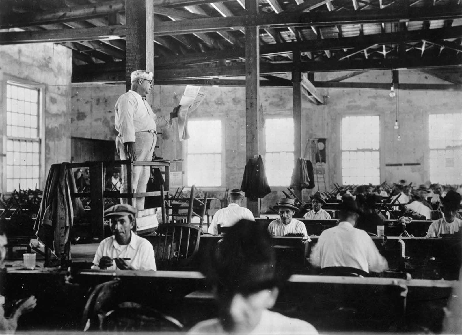 A lector reads a newspaper to workers in a Key West, Florida cigar factory. 1930.